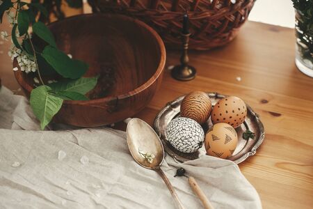 Zero waste Easter. Natural Easter eggs with modern wax ornaments on vintage plate on background of...