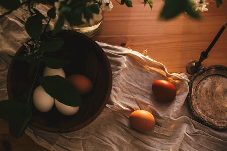 Rural Easter flat lay. Natural eggs and vintage candle on linen fabric on rustic table with cherry...