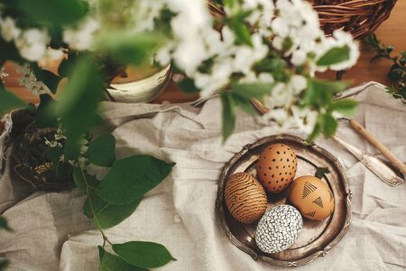 Happy Easter. Stylish Rural flat lay. Natural Easter eggs with modern wax ornaments on vintage plate...