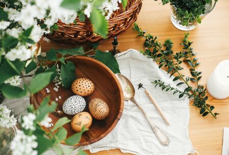 Happy Easter flat lay, zero waste. Natural Easter eggs painted with wax in wooden bowl on background...
