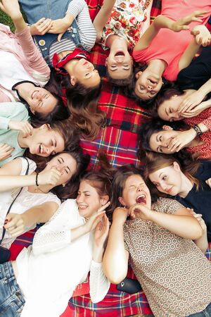 happy group of women faces in circle laughing and having fun on picnic top view, lying on blanket, joyful moments celebration in summer parkの写真素材