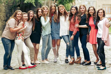 Group of happy stylish women posing on background of old european city street, travel or celebrating...