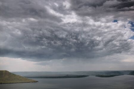 Beautiful view on big lake among hills and rain from clouds. River and cliffs landscape. Bakota lake...