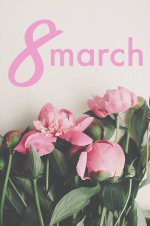 8 March text. 8 march lettering on stylish pink peonies rustic flat lay. Floral greeting card. Happy...