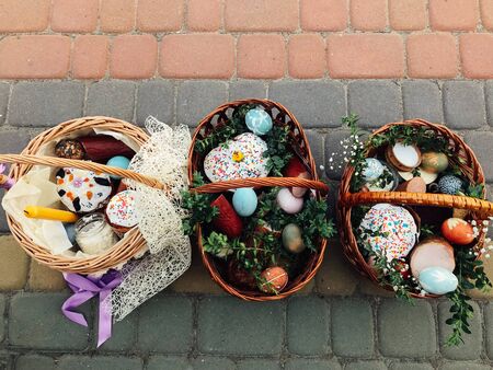 Traditional orthodox Easter food for blessing. Easter baskets with stylish painted eggs, easter cake, ham,beets, butter, candle with boxwood branches for sanctify at church.の写真素材