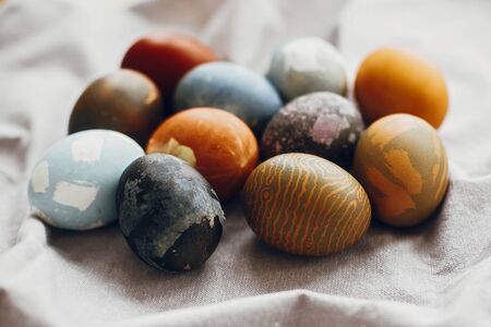 Stylish easter eggs on rustic table. Natural dyed colorful easter eggs  on rural linen textile background. Space for textの写真素材