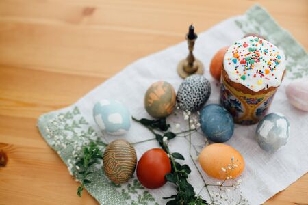 Homemade easter cake and stylish easter eggs natural dyed on rustic cloth with flowers and green...