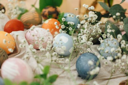 Easter eggs with modern minimal ornaments painted with natural dye on rustic background. Stylish colorful Easter eggs on wooden table with spring flowers and green branches. Zero waste holidayの写真素材