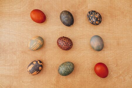 Modern Easter eggs flat lay on rustic wooden background. Stylish brown and stone Easter eggs with...