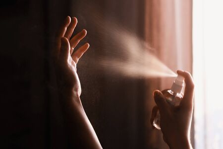 Disinfecting hands. Person using antiseptic spray on hands to  prevent coronavirus or flu disease....