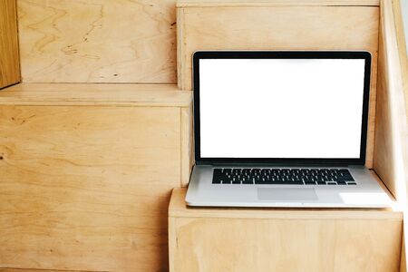 Laptop with blank white screen on modern wooden stairs with copy space, in modern room.Working online from home mockup. Freelance concept. Shopping online. Staying home. Blog templateの写真素材