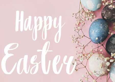Happy Easter text. Easter greetings card. Stylish easter eggs and spring flowers border on pink...