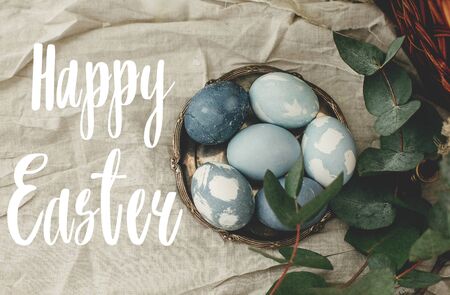 Happy Easter text. Easter greetings lettering. Modern blue Easter eggs on vintage plate on rustic...