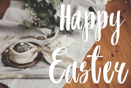 Happy Easter text. Easter greetings lettering. Stylish Easter egg in bunny ears napkin and flowers...