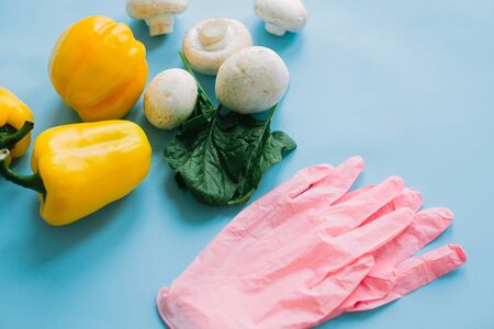 Safe shopping in quarantine. Pink gloves with vegetables on blue background. Order food online with delivery and stay home. Prevention of virus epidemic. Stay safe.の写真素材