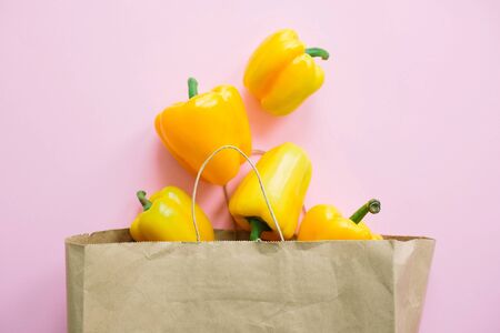 Bell peppers in paper bag on pink background flat lay. Zero waste shopping, plastic free. Shopping groceries online. Order fresh organic food and get them delivered safe. Stay homeの写真素材