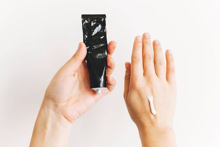 Avoiding dry skin. Hands holding cream in black tube for moisturizing skin after using disinfectant and alcohol gel. Treatment for dry skin. Luxury skin care. Hand creamの写真素材