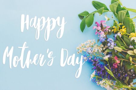 Happy Mother's day greeting card. Colorful spring flowers border on blue background flat lay with greeting text. Floral greeting card. Happy Mothers day stylish flat layの写真素材