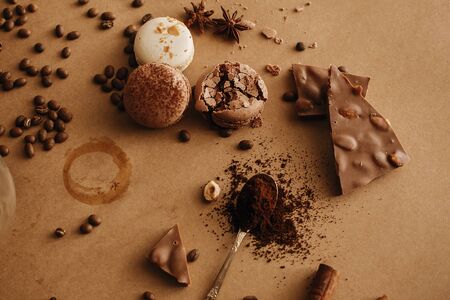 Coffee trace and roasted beans,ground coffee on spoon, macarons, chocolate, cinnamon on brown...