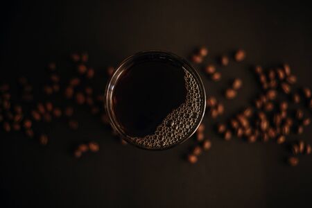 Fresh coffee in glass cup with coffee beans on black