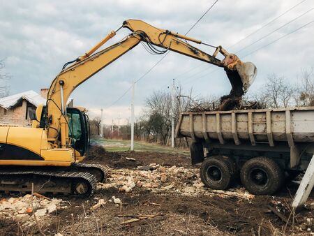 Bulldozer clearing land from old bricks and concrete from walls with dirt and trash. Backhoe...