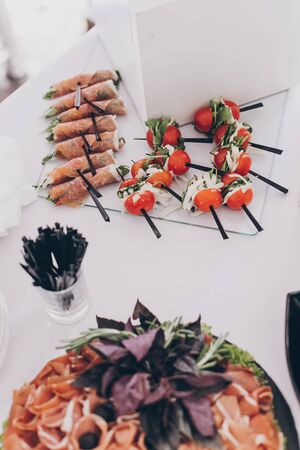 Delicious appetizer and canape on table at wedding reception in restaurant. Luxury catering service. Italian delicatessen, prosciutto snacks, cheese and olives. Christmas feastの写真素材