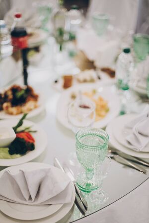 Wedding luxury table setting at reception in restaurant. Stylish glasses for wine, plate with napkin, cutlery and food on tables. Luxury catering service. Christmas feastの写真素材