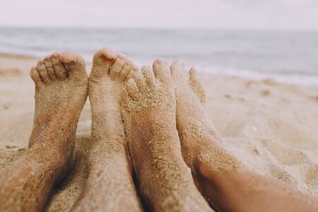 Couple legs in sand close up on sunny beach. Couple in love relaxing together on sandy seashore. Family summer vacation or honeymoon precious moments. Authentic imageの写真素材