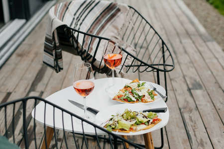Homemade pizza and aperol drink on modern wooden terrace, dinner for two. Delicious pizza and cocktails for home celebration. Summer vacation and resort.の写真素材