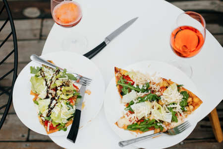 Homemade pizza and  drink on modern white table on terrace, dinner for two. Delicious pizza and cocktails for home or cafe celebration. Summer vacation and resort.の写真素材