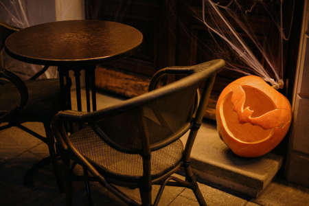 Halloween street decor. Carved pumpkin with scary bat and cobweb in dark. Modern festive decoration...
