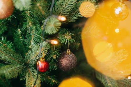 Modern decorated Christmas tree with red and gold baubles and festive lights. Hanging shiny glitter ornaments on christmas tree,  scandinavian room decor for winter holidaysの写真素材