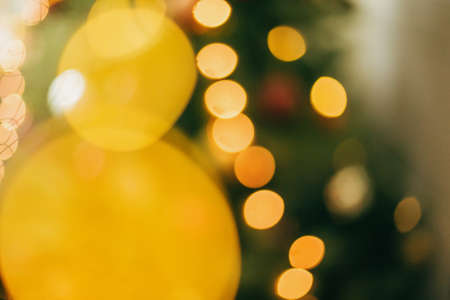 Abstract Christmas background. Blurred image of christmas tree and golden lights. Yellow illumination bokeh on green backdrop. Merry Christmas and Happy Holidaysの写真素材