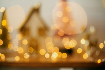 Abstract Christmas background. Blurred image of house and glitter trees in golden festive lights....