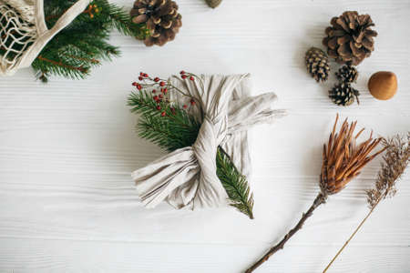 Zero waste christmas flat lay. Stylish christmas gift wrapped in linen fabric, decorated with...