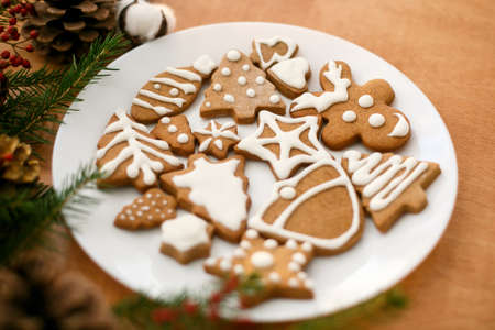Christmas gingerbread cookies on white plate on wooden background with fir branches and cones.Tasty...