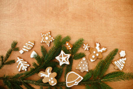 Christmas gingerbread cookies and fir branches border on  wooden background. Season's greeting card flat lay with space for text. Merry Christmas and Happy Holidays!の写真素材
