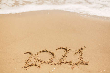 Hello 2021! Happy new year 2021 sign on sandy beach with waves and white foam. Welcoming 2021 with new resolutions, dreams, lists!の写真素材