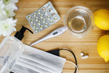 Vitamin D, vitamin C and zinc pills on wooden table with face mask, disinfection gel in bottle,...