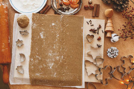 Raw gingerbread  dough, metal cutters ,flour, wooden rolling pin, spices, oranges, festive decorations on rustic table. Making gingerbread cookies flat lay, Christmas holiday tradition, adventの写真素材