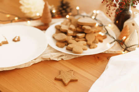 Making gingerbread cookies. Baked christmas cookies on rustic table with lights. Christmas holiday...