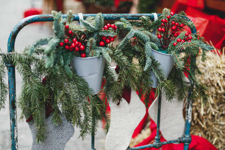 Stylish christmas branches and red berries with stockings, rustic decor at storefront or building. Christmas festive street decor, holiday winter fair. Merry Christmasの写真素材