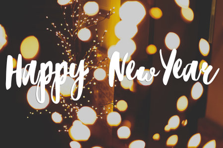 Happy New Year text handwritten on stylish illuminated tree with warm golden lights. Greeting card, modern seasons greetingsの写真素材