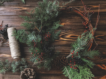Christmas rustic wreath with thread, pinecones and berries on wooden rustic table. Happy holidays and Merry Christmas!の写真素材