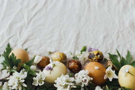 Happy Easter! Easter eggs with spring flowers on rustic linen background with space for text....