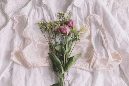 Happy Women's day. Woman essentials, fragrance. Stylish lace lingerie and spring flowers on shirt on bed. Soft trendy feminine image, sensual mood at home concept.の写真素材
