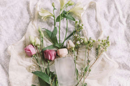 Woman essentials, fragrance. Stylish lace lingerie, modern jewelry, perfume bottle and spring flowers on bed. Soft trendy feminine image, sensual mood at home concept. Happy Women's dayの写真素材
