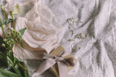 Happy Women's day. Stylish lace lingerie, gift box, modern jewelry and spring bouquet on bed. Soft trendy feminine image, sensual mood at home concept. Woman essentialsの写真素材