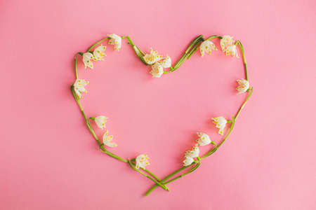 Happy Mothers day and love concept. Floral heart made of spring flowers on pink paper flat lay. Stylish spring greeting card with copy space. Happy valentines day. White spring snowflakesの写真素材