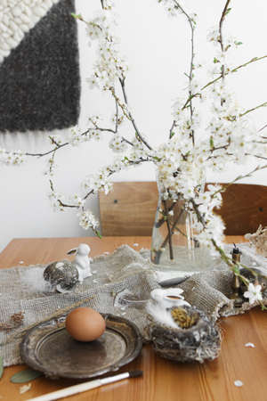 Happy Easter! Natural Easter eggs, white bunnies, feathers, nest and cherry blooming branch with...
